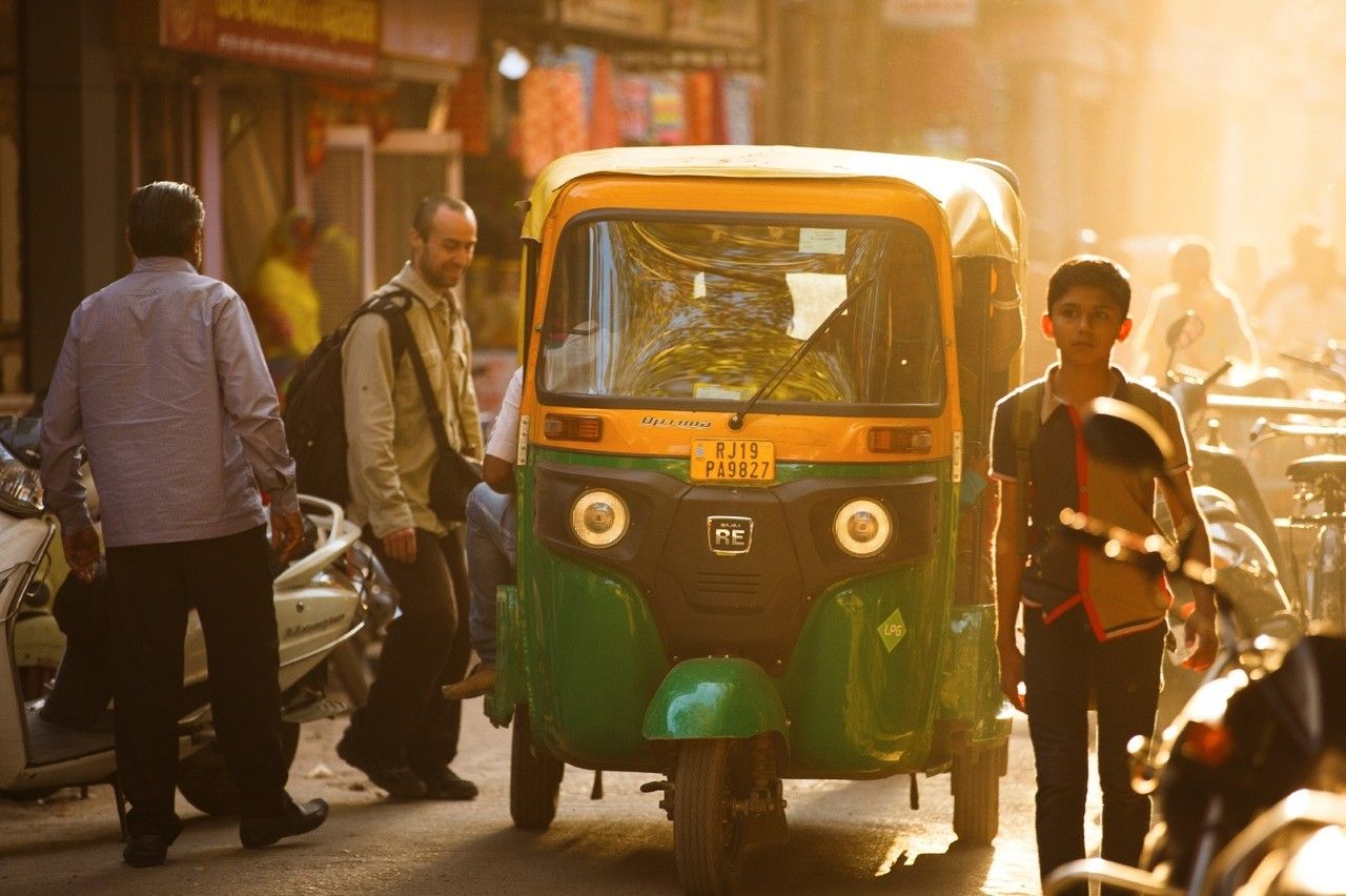 Ein Tuk Tuk Taxi teilt sich eine schmale Straße mit Fußgängern